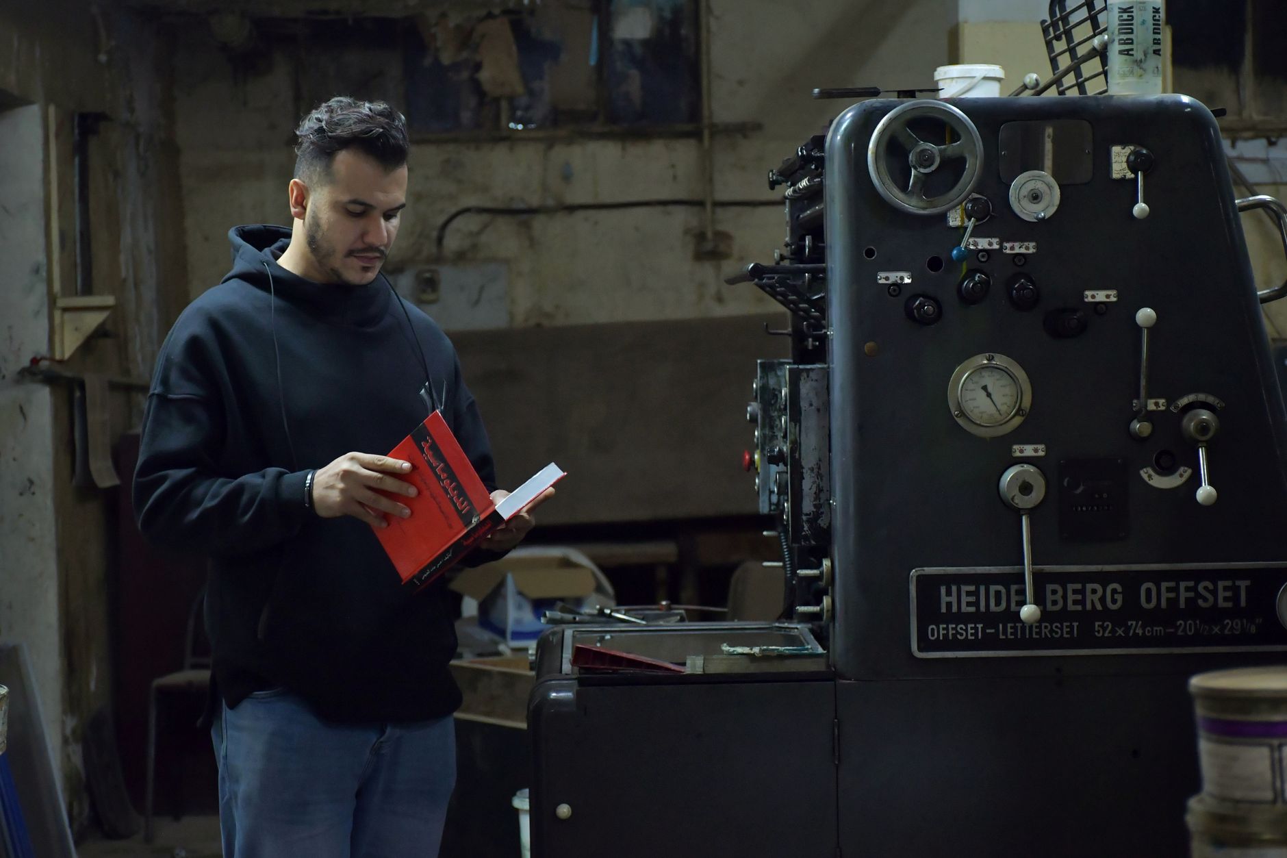 Maestro impresor revisando un pliego junto a una prensa offset (foto de ambiente, provisional)